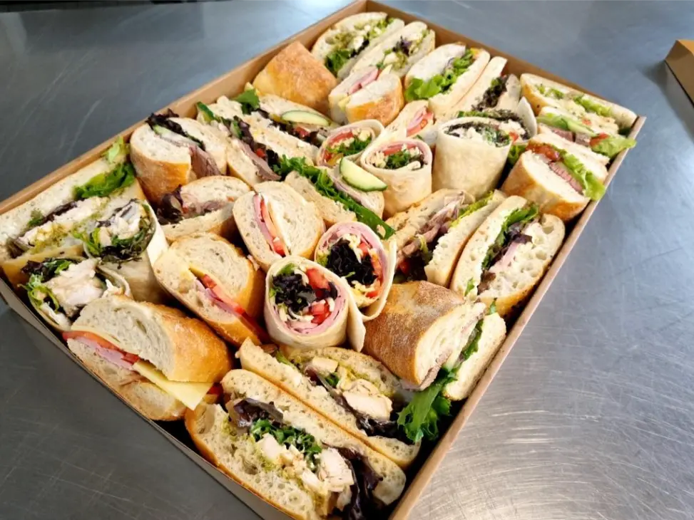 Sliced ham and salad wraps arranged in a kraft catering box