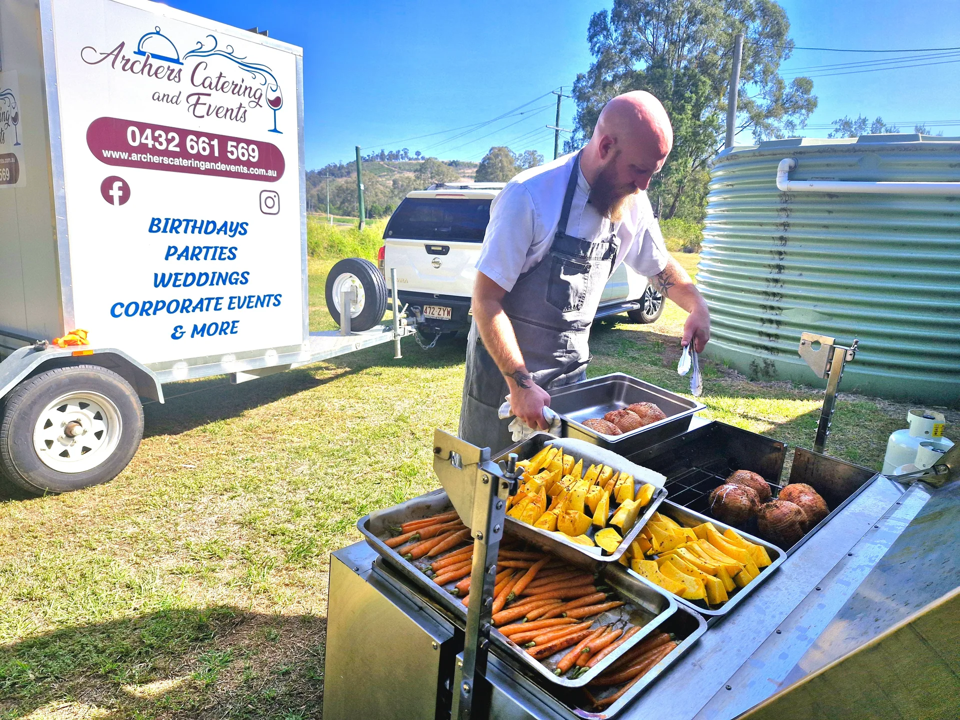 Chef Adam Archer cooking at an outdoor event beside the Archers Catering and Events trailer