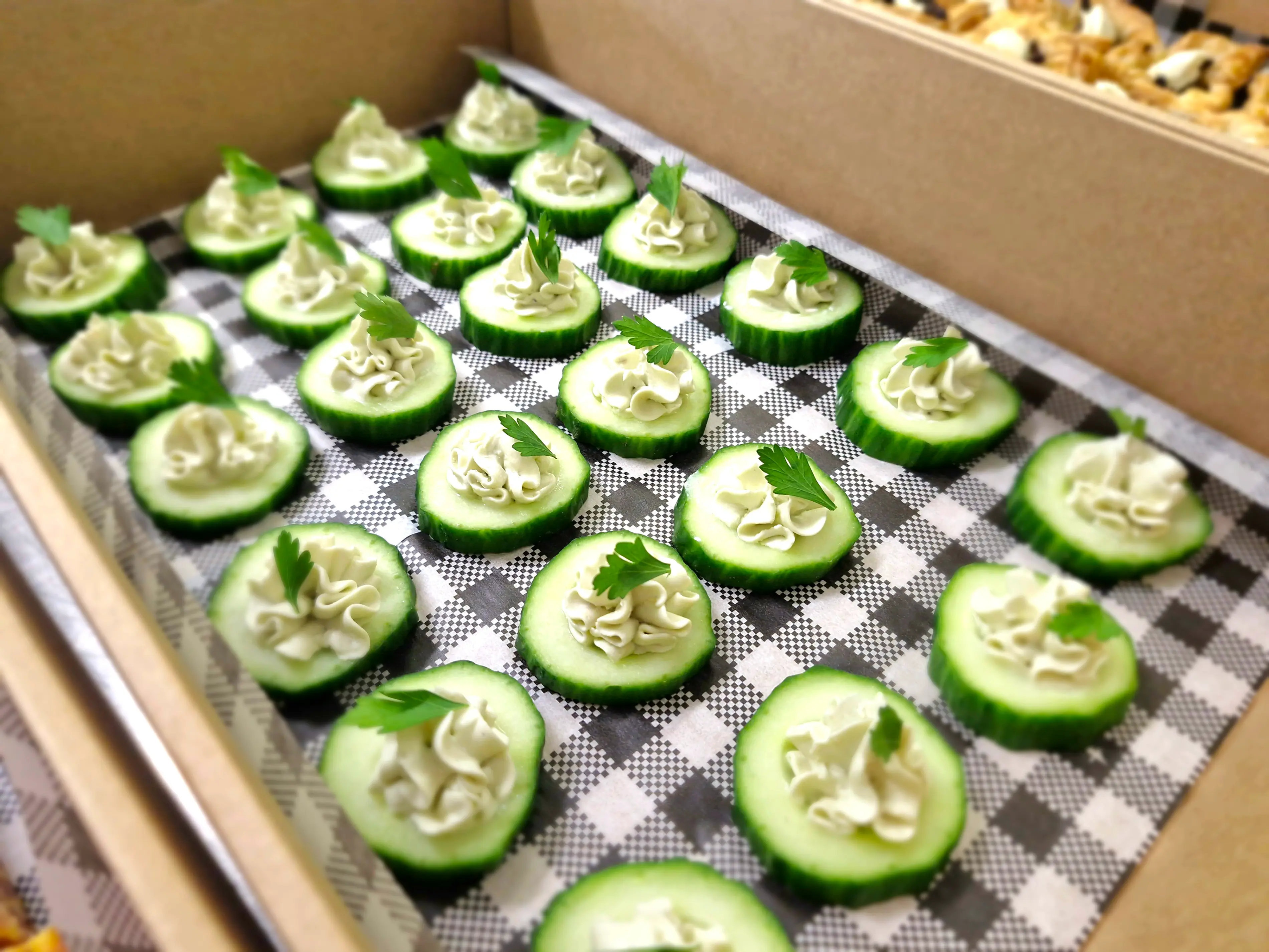 Trays of assorted canapés including pastry tarts and cucumber rounds ready for corporate service