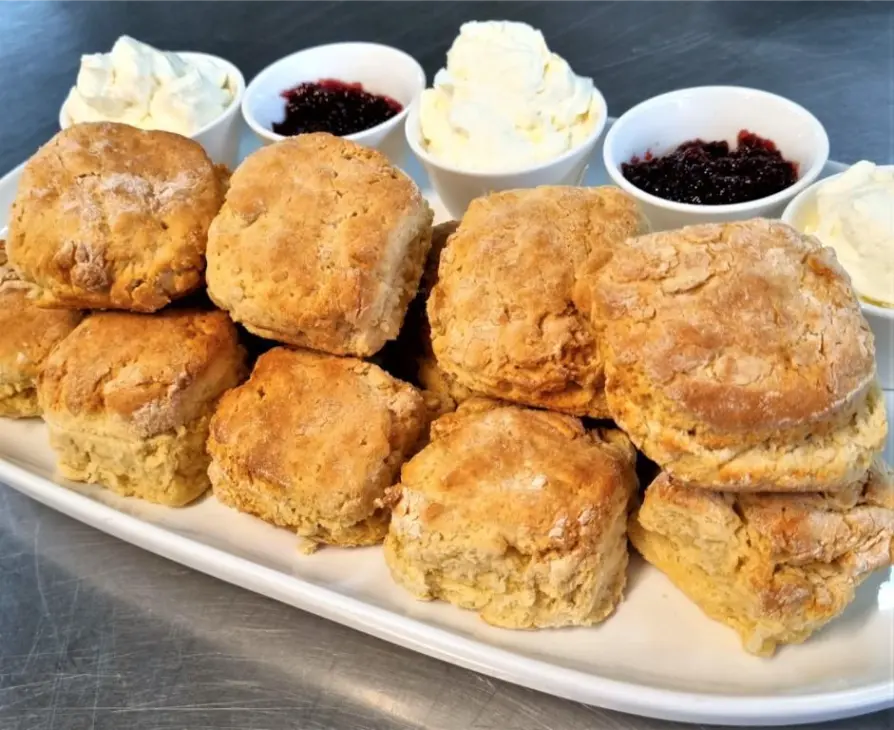 Tiered stand of freshly baked scones with jam and cream for a high tea catering event