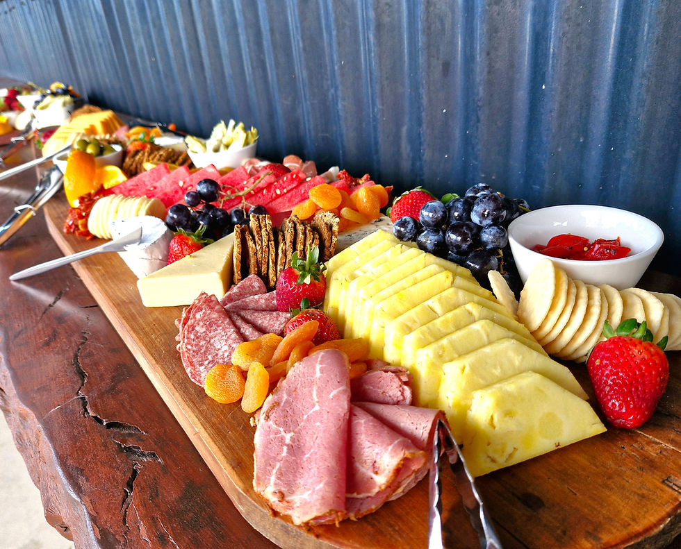 A grazing board arranged on a rustic board with cheese, cured meats, crackers and fruit for a wedding reception